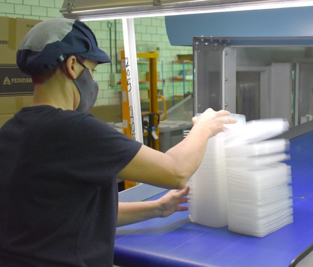 Fedinsa : Ouvrière pendant le processus de fabrication de contenants en plastique transparent.